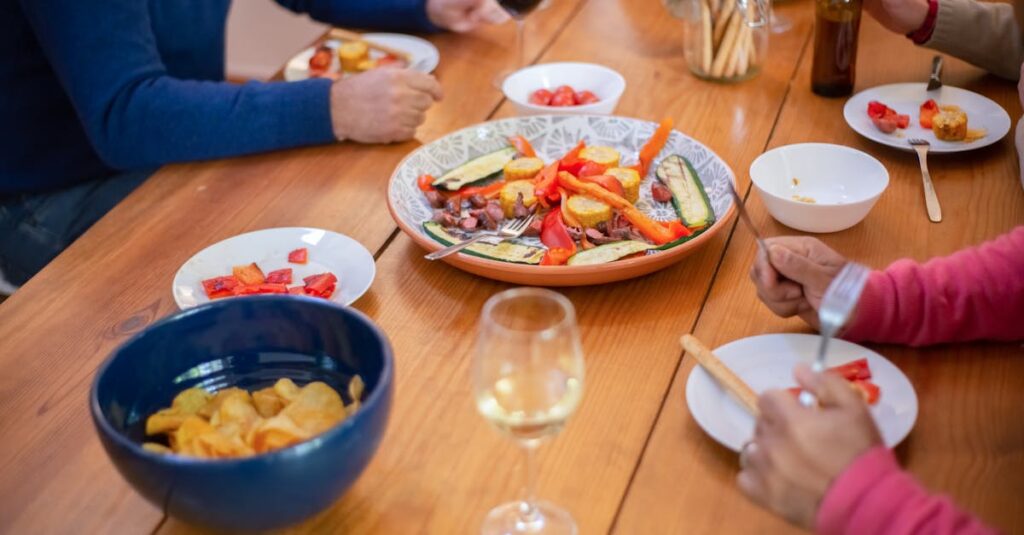 Casual dinner party with friends sharing food and drinks around a wooden table.