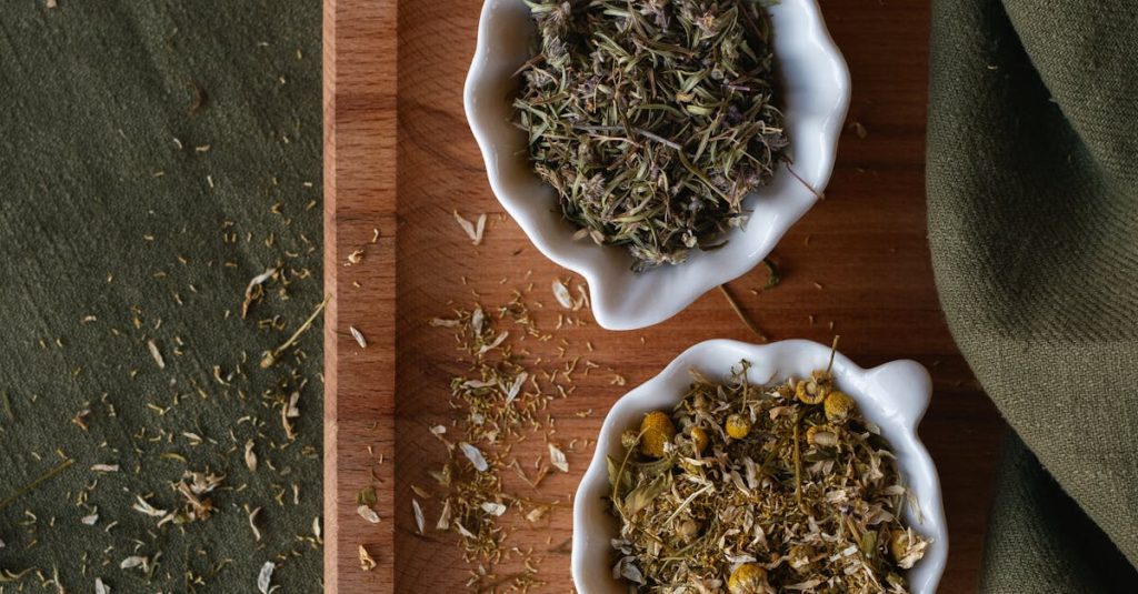 Dried chamomile and herbs in white bowls on a wooden tray, perfect for herbal tea themes.