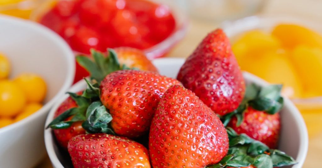 Vibrant fresh strawberries and assorted berries in bowls, showcasing a vibrant summer fruit display.