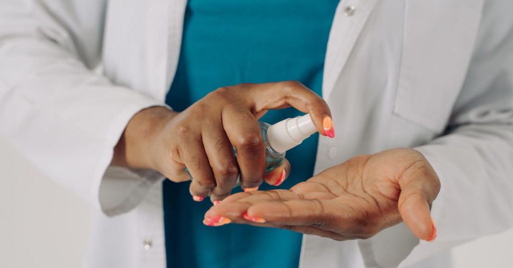 Close-up of a healthcare worker applying hand sanitizer for hygiene and safety.