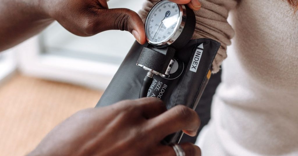 Healthcare professional using blood pressure monitor on patient during check-up.