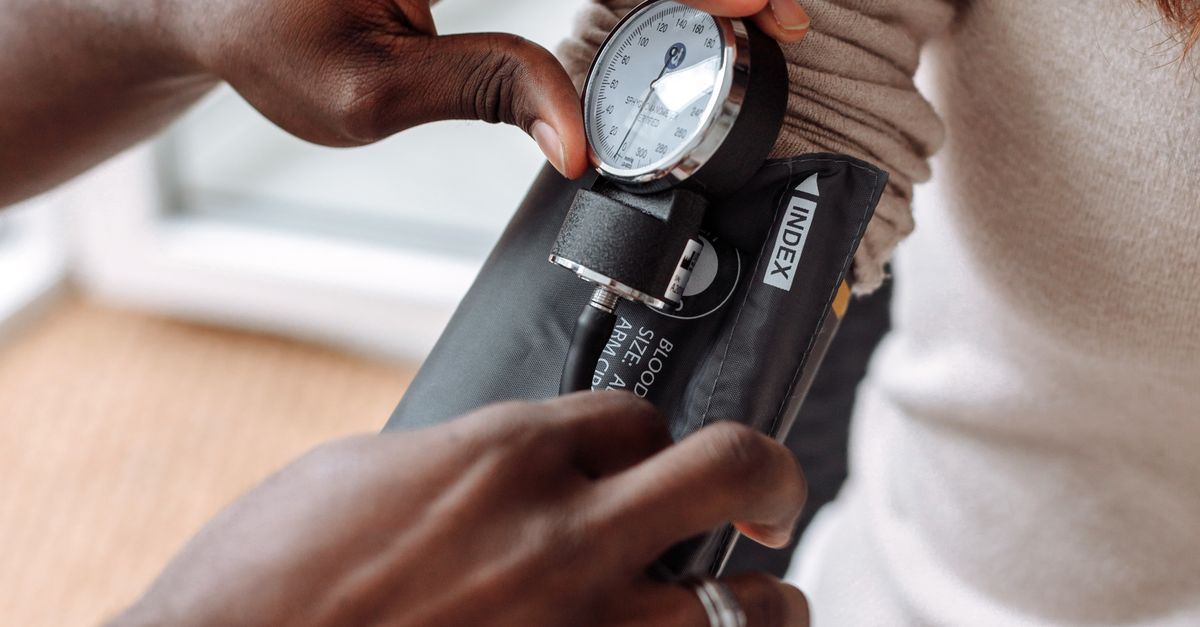 Healthcare professional using blood pressure monitor on patient during check-up.
